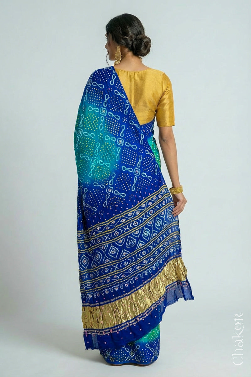 Model wearing Handcrafted Peacock Blue Ombre Bandhani Gaji Silk Saree with rai bandhej patterns and mirror, sequins embroidery.