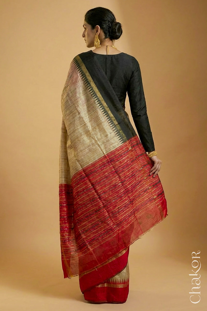 Back pose of woman wearing a traditional red and Natural tussar silk handloom temple border saree.