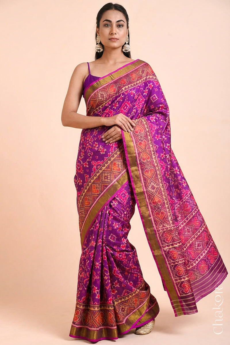 Model wearing Handloom Magenta Pink Rajkoti Patola Ikat Mulberry Silk Saree with tissue borders, woven using traditional designs in Gujarat.