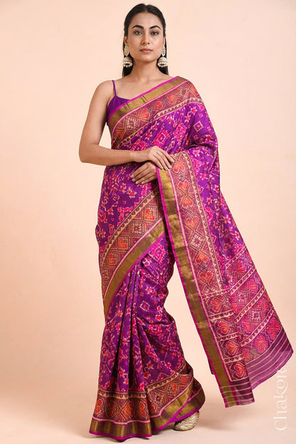 Model wearing Handloom Magenta Pink Rajkoti Patola Ikat Mulberry Silk Saree with tissue borders, woven using traditional designs in Gujarat.