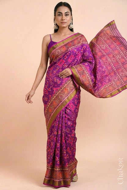 Model wearing Handloom Magenta Pink Rajkoti Patola Ikat Mulberry Silk Saree with tissue borders, woven using traditional designs in Gujarat.