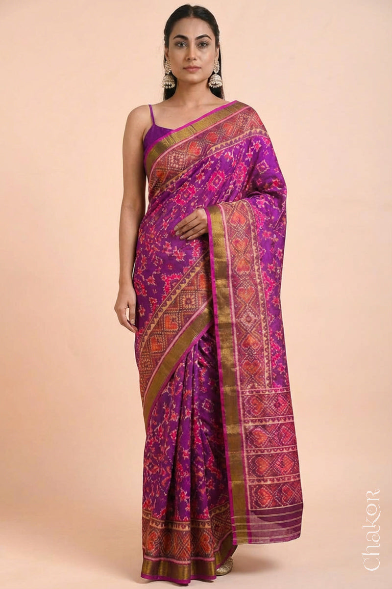 Model wearing Handloom Magenta Pink Rajkoti Patola Ikat Mulberry Silk Saree with tissue borders, woven using traditional designs in Gujarat.