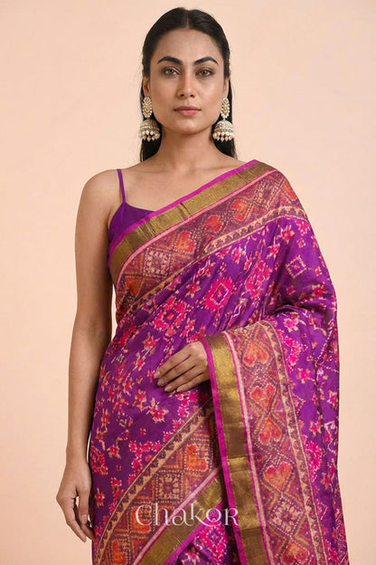 Model wearing Handloom Magenta Pink Rajkoti Patola Ikat Mulberry Silk Saree with tissue borders, woven using traditional designs in Gujarat.
