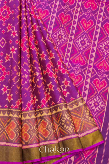 Close up of Handloom Magenta Pink Rajkoti Patola Ikat Mulberry Silk Saree with tissue borders, woven using traditional designs in Gujarat.
