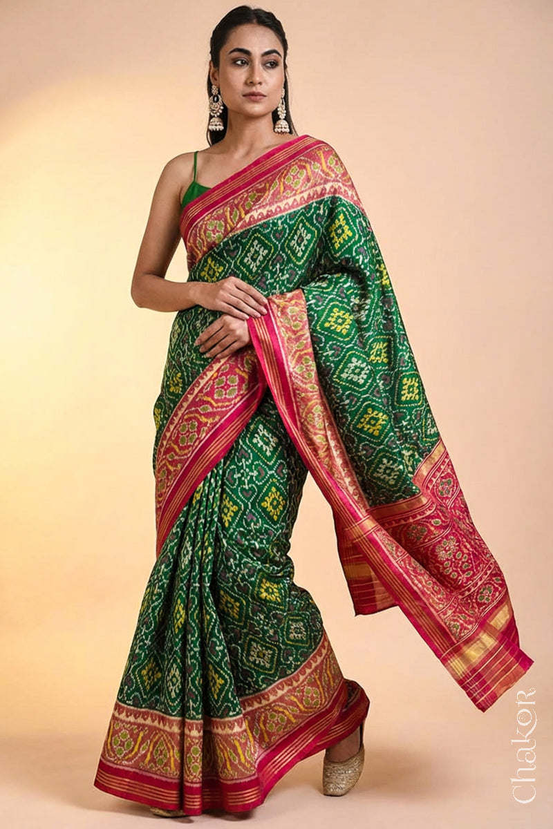 Model wearing Handloom Green Patola Ikat Mulberry Silk Saree with red border pallu, woven using traditional designs in Rajkot.