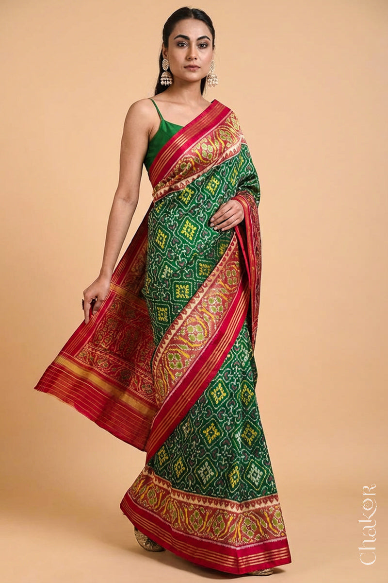 Model wearing Handloom Green Patola Ikat Mulberry Silk Saree with red border pallu, woven using traditional designs in Rajkot.