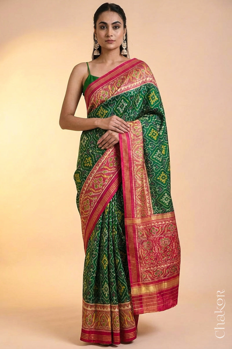 Model wearing Handloom Green Rajkoti Patola Ikat Mulberry Silk Saree with red border pallu, woven using traditional designs in Gujarat.