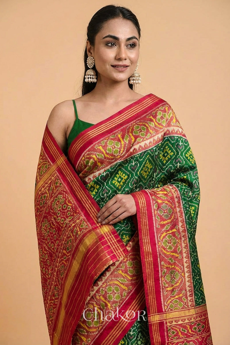 Model wearing Handloom Green Patola Ikat Mulberry Silk Saree with red border pallu, woven using traditional designs in Rajkot.