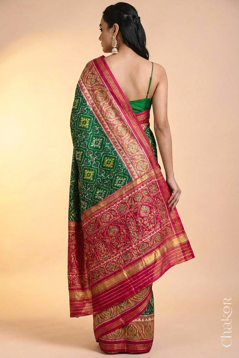 Model wearing Handloom Green Rajkoti Patola Ikat Mulberry Silk Saree with red border pallu, woven using traditional designs in Gujarat.