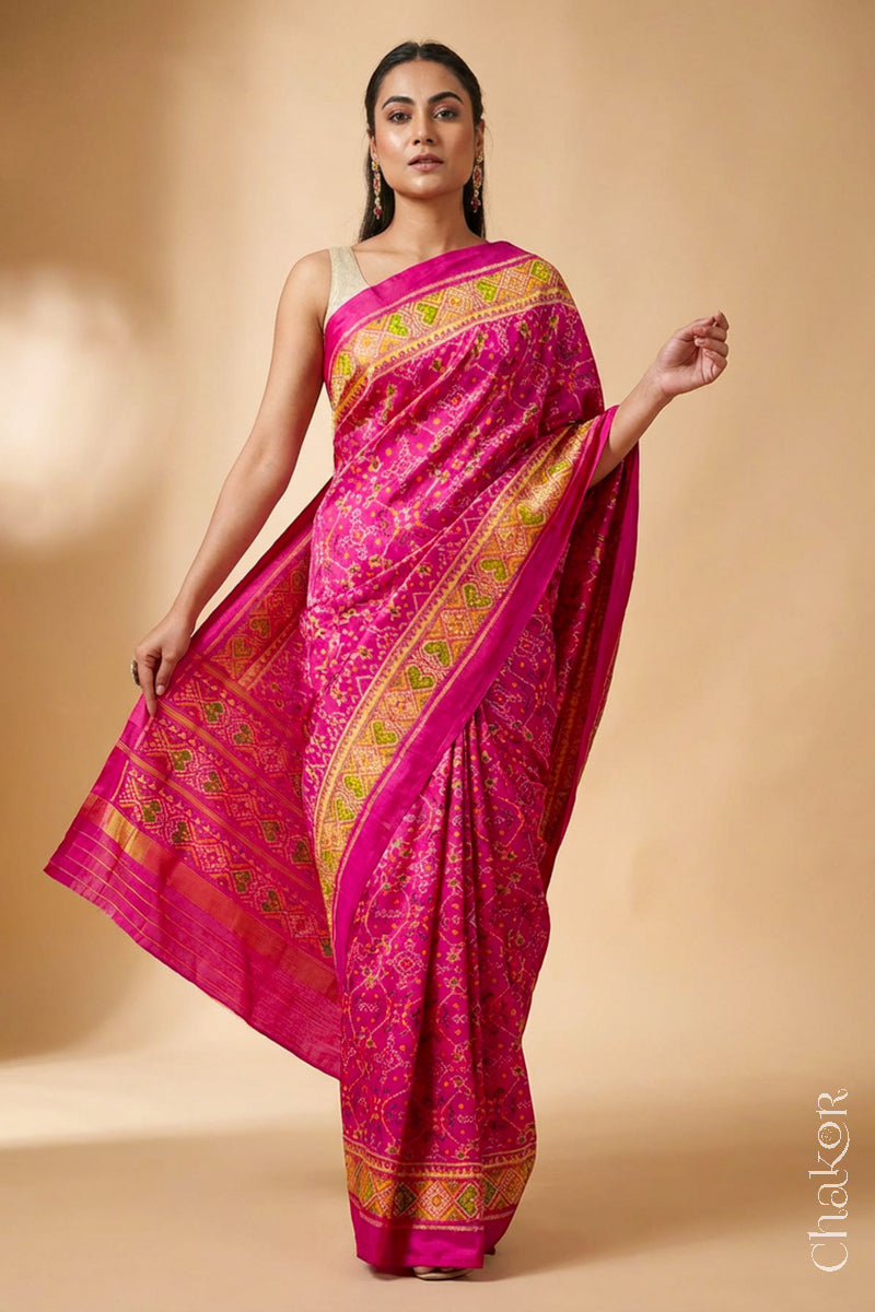 Model wearing Handloom Rani Pink Rajkoti Patola Ikat Mulberry Silk Saree with tissue borders, and mauve pallu woven using traditional designs in Gujarat.
