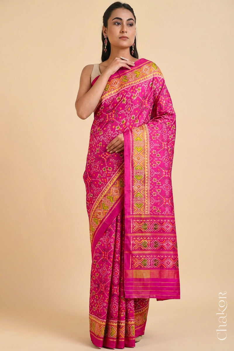 Model wearing Handloom Rani Pink Rajkoti Patola Ikat Mulberry Silk Saree with tissue borders, and mauve pallu woven using traditional designs in Gujarat.