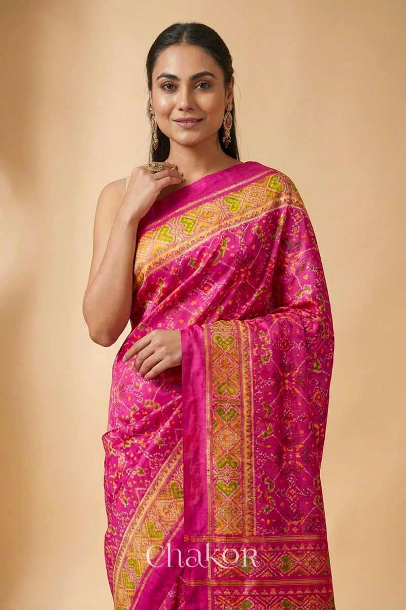 Model wearing Handloom Rani Pink Rajkoti Patola Ikat Mulberry Silk Saree with tissue borders, and mauve pallu woven using traditional designs in Gujarat.