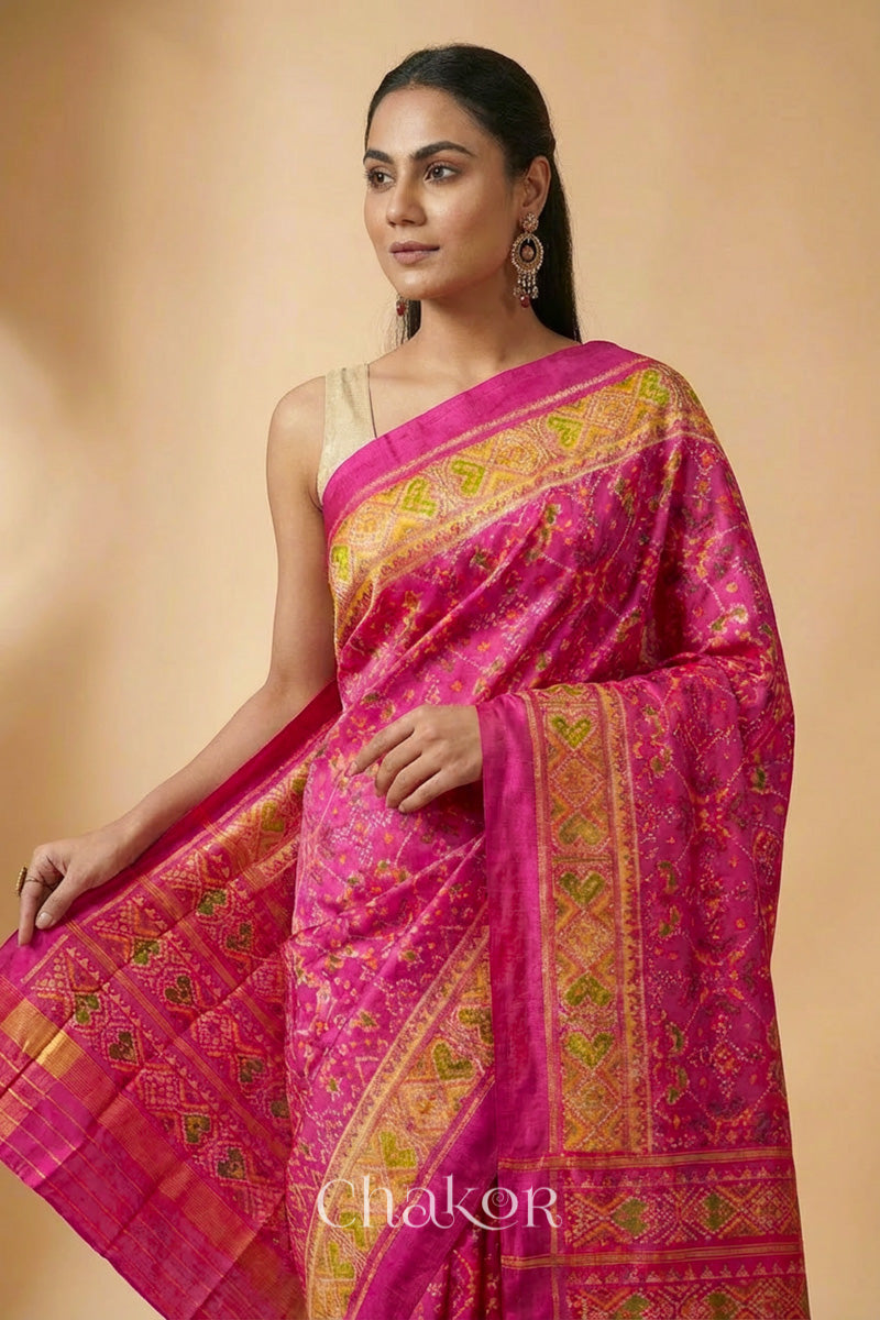 Model wearing Handloom Rani Pink Rajkoti Patola Ikat Mulberry Silk Saree with tissue borders, and mauve pallu woven using traditional designs in Gujarat.