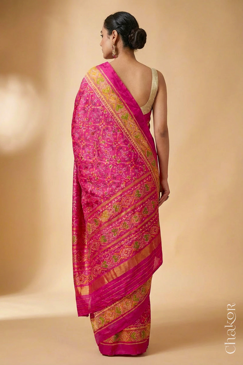 Model wearing Handloom Rani Pink Rajkoti Patola Ikat Mulberry Silk Saree with tissue borders, and mauve pallu woven using traditional designs in Gujarat.