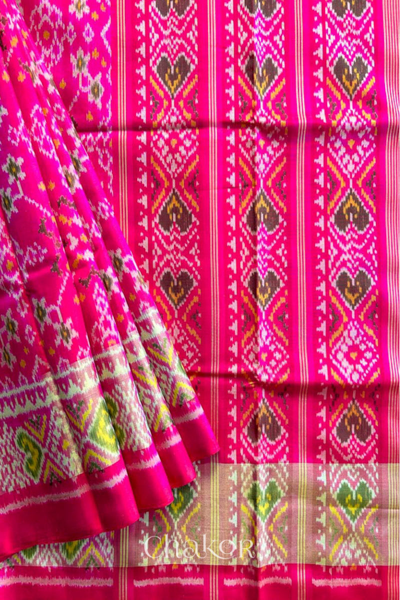 Close up of Handloom Rani Pink Rajkoti Patola Ikat Mulberry Silk Saree with tissue borders, and mauve pallu woven using traditional designs in Gujarat.