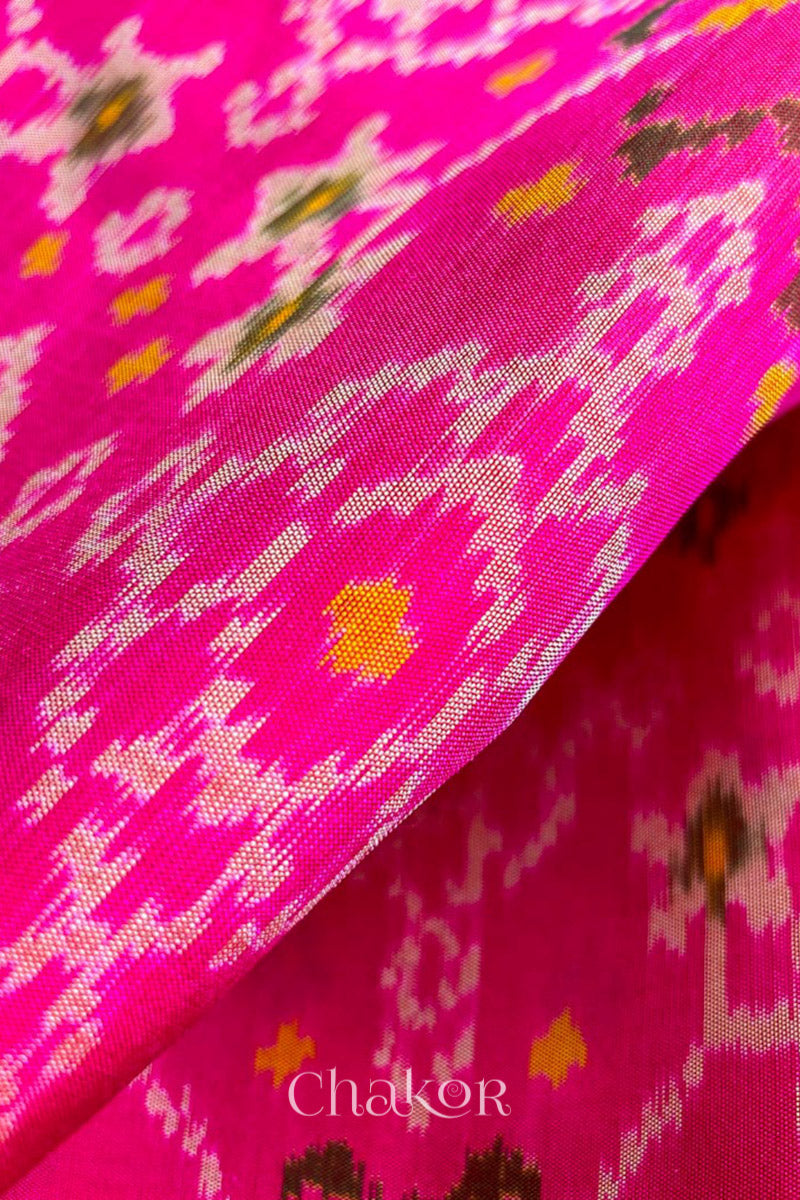 Close up of Handloom Rani Pink Rajkoti Patola Ikat Mulberry Silk Saree with tissue borders, and mauve pallu woven using traditional designs in Gujarat.