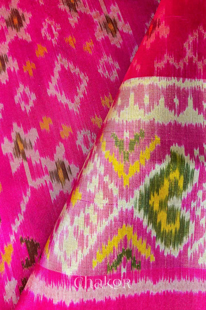 Close up of Handloom Rani Pink Rajkoti Patola Ikat Mulberry Silk Saree with tissue borders, and mauve pallu woven using traditional designs in Gujarat.