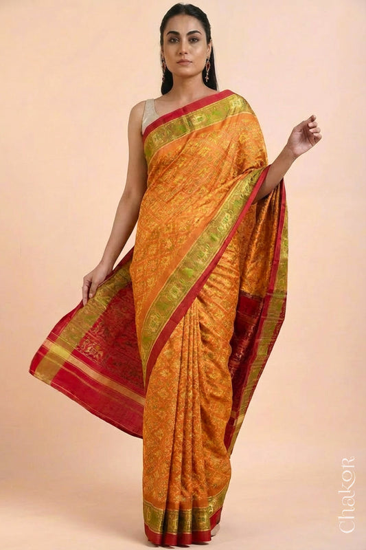 Model wearing Handloom Rust Rajkoti Patola Ikat Mulberry Silk Saree with Red borders & pallu, woven using traditional designs in Gujarat.