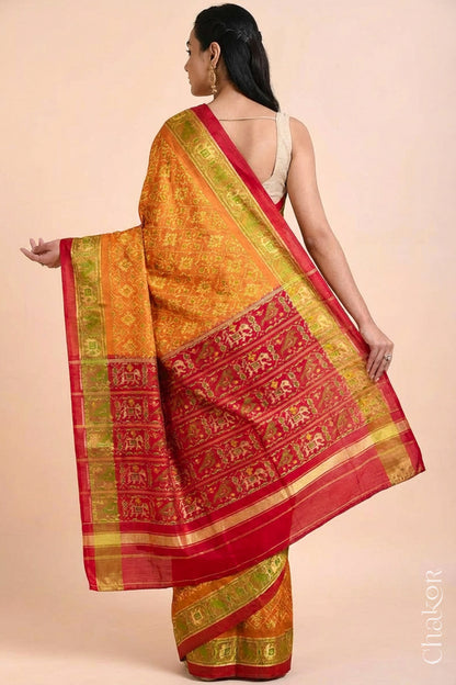 Model wearing Handloom Rust Rajkoti Patola Ikat Mulberry Silk Saree with Red borders & pallu, woven using traditional designs in Gujarat.