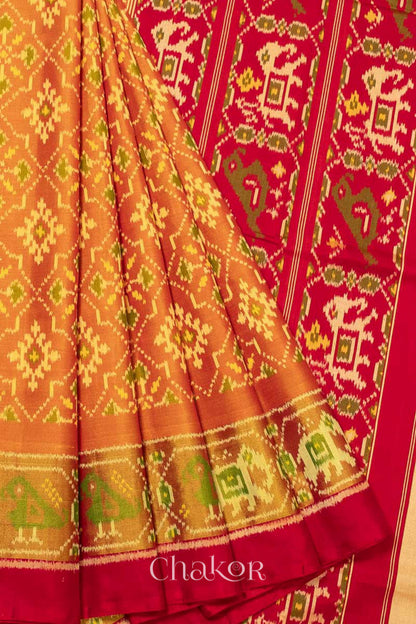 Close up of Handloom Rust Rajkoti Patola Ikat Mulberry Silk Saree with Red borders & pallu, woven using traditional designs in Gujarat.