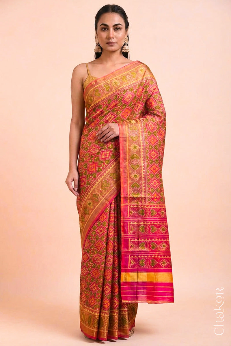 Model wearing Handloom Coral Peach Rajkoti Patola Ikat Mulberry Silk Saree with tissue borders, woven using traditional designs in Gujarat.