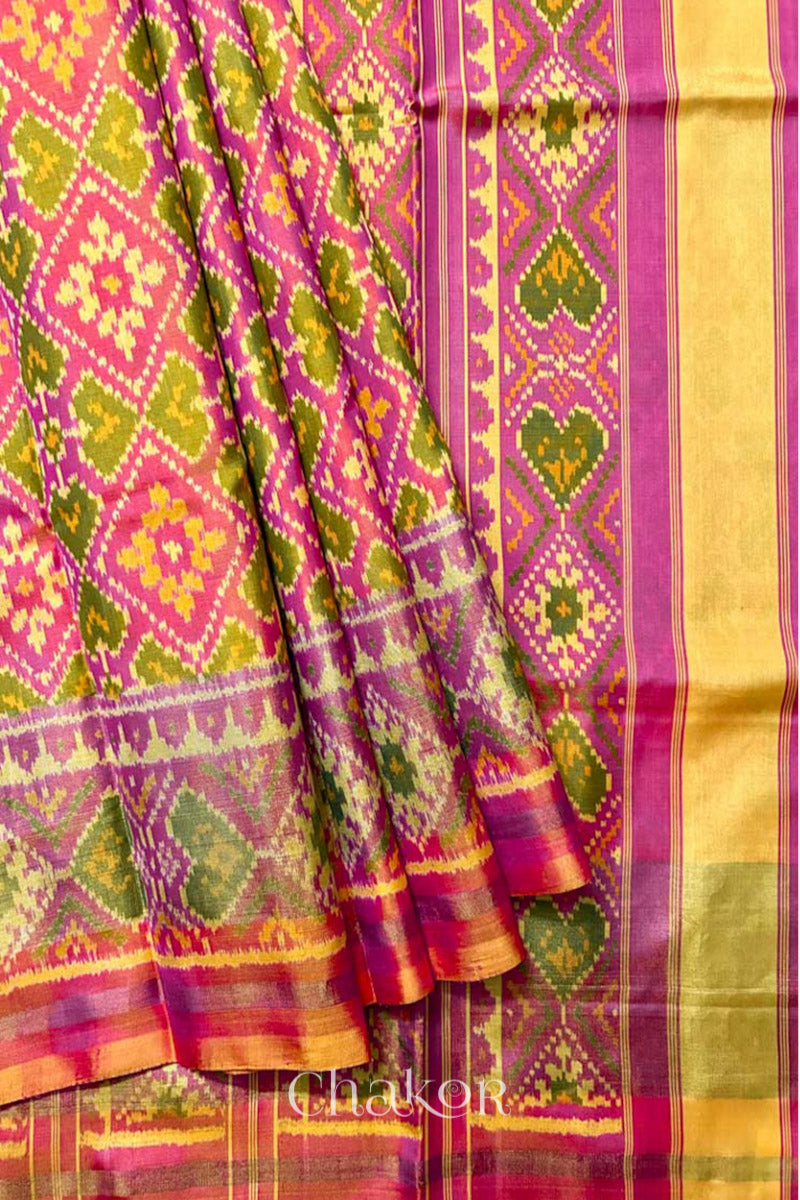 Close up of Handloom Coral Peach Rajkoti Patola Ikat Mulberry Silk Saree with tissue borders, and pink pallu woven using traditional designs in Gujarat.