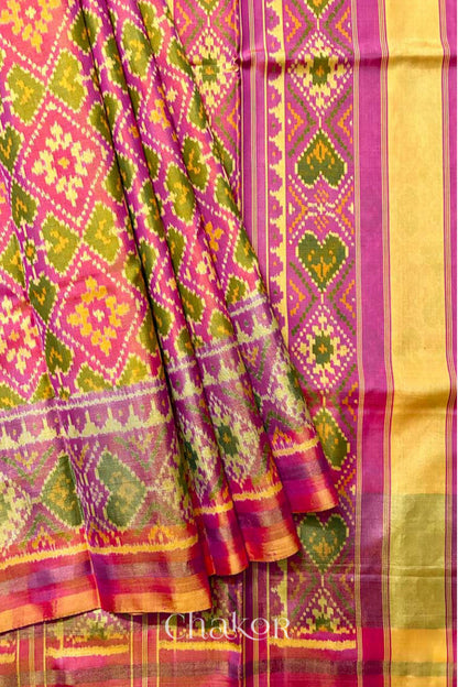 Close up of Handloom Coral Peach Rajkoti Patola Ikat Mulberry Silk Saree with tissue borders, and pink pallu woven using traditional designs in Gujarat.