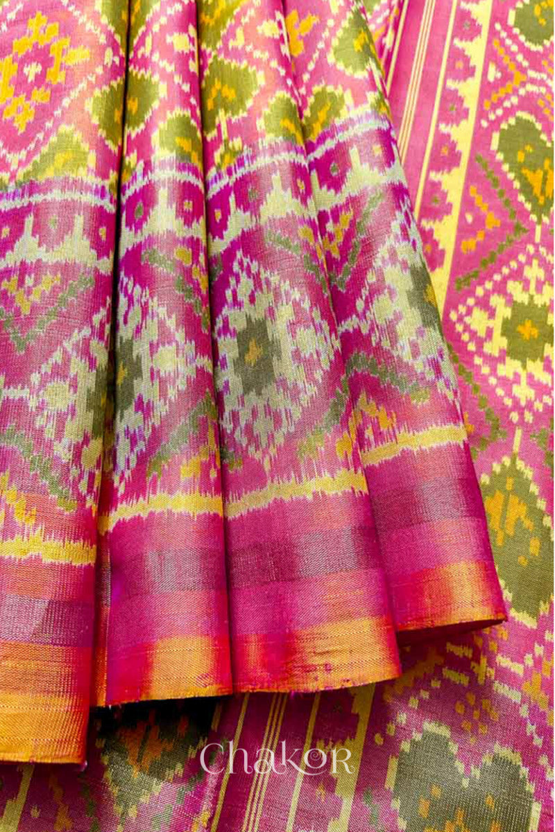 Close up of Handloom Coral Peach Rajkoti Patola Ikat Mulberry Silk Saree with tissue borders, and pink pallu woven using traditional designs in Gujarat.