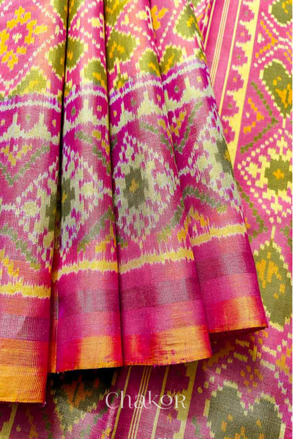 Close up of Handloom Coral Peach Rajkoti Patola Ikat Mulberry Silk Saree with tissue borders, and pink pallu woven using traditional designs in Gujarat.