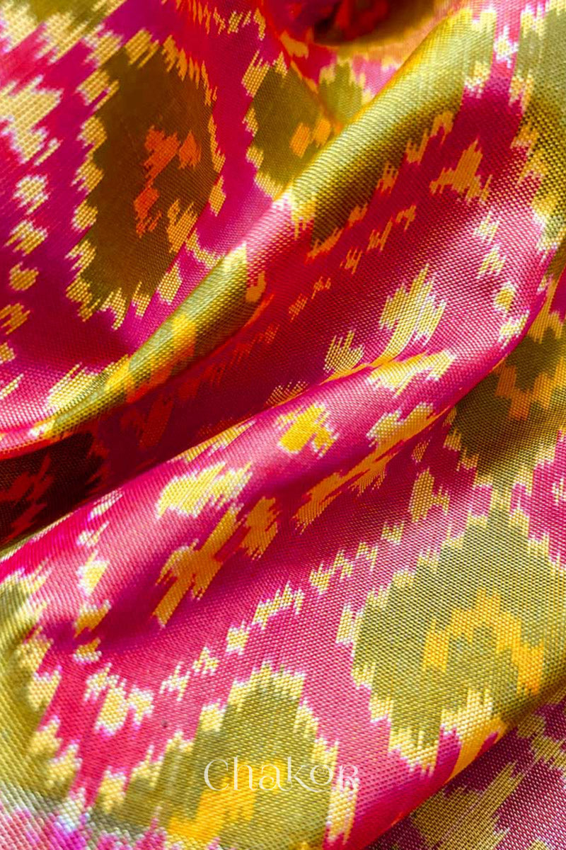 Close up of Handloom Coral Peach Rajkoti Patola Ikat Mulberry Silk Saree with tissue borders, and pink pallu woven using traditional designs in Gujarat.
