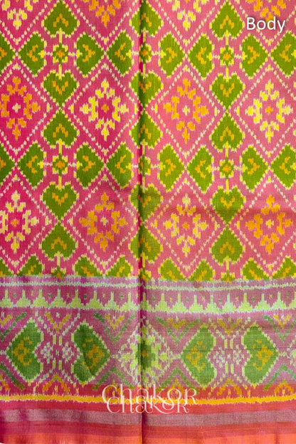 Close up of Handloom Coral Peach Rajkoti Patola Ikat Mulberry Silk Saree with tissue borders, and pink pallu woven using traditional designs in Gujarat.