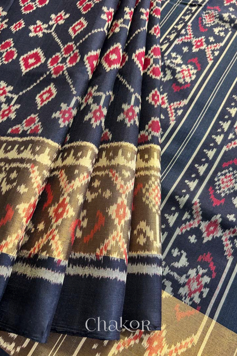 Pleats and pallu view of Handloom Black Patola Ikkat Mulberry Silk Saree with traditional patterns in red floral motifs.