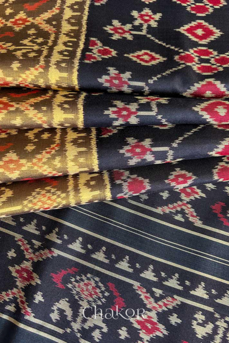 Pleats and pallu view of Handloom Black Patola Ikkat Mulberry Silk Saree with traditional patterns in red floral motifs.