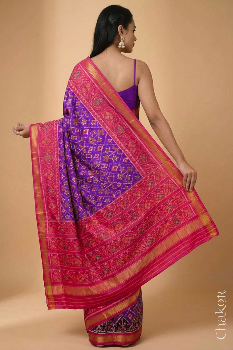 Model wearing Handloom Purple Pink Ikat Patola Mulberry Silk Saree with traditional design.