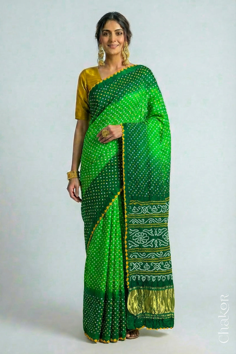 Woman wearing Handcrafted Parrot and green ombre Bandhani Gaji Silk Saree with traditional bandhej patterns and mukaish embroidery.