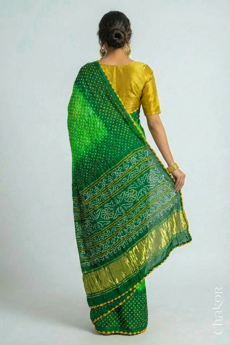 Woman wearing Handcrafted Parrot and green ombre Bandhani Gaji Silk Saree with traditional bandhej patterns and mukaish embroidery.