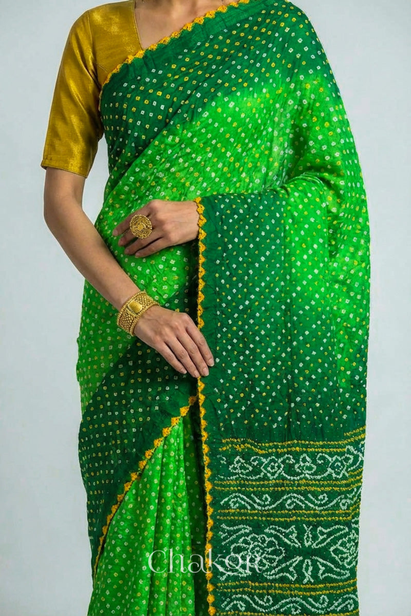 Woman wearing Handcrafted Parrot and green ombre Bandhani Gaji Silk Saree with traditional bandhej patterns and mukaish embroidery.