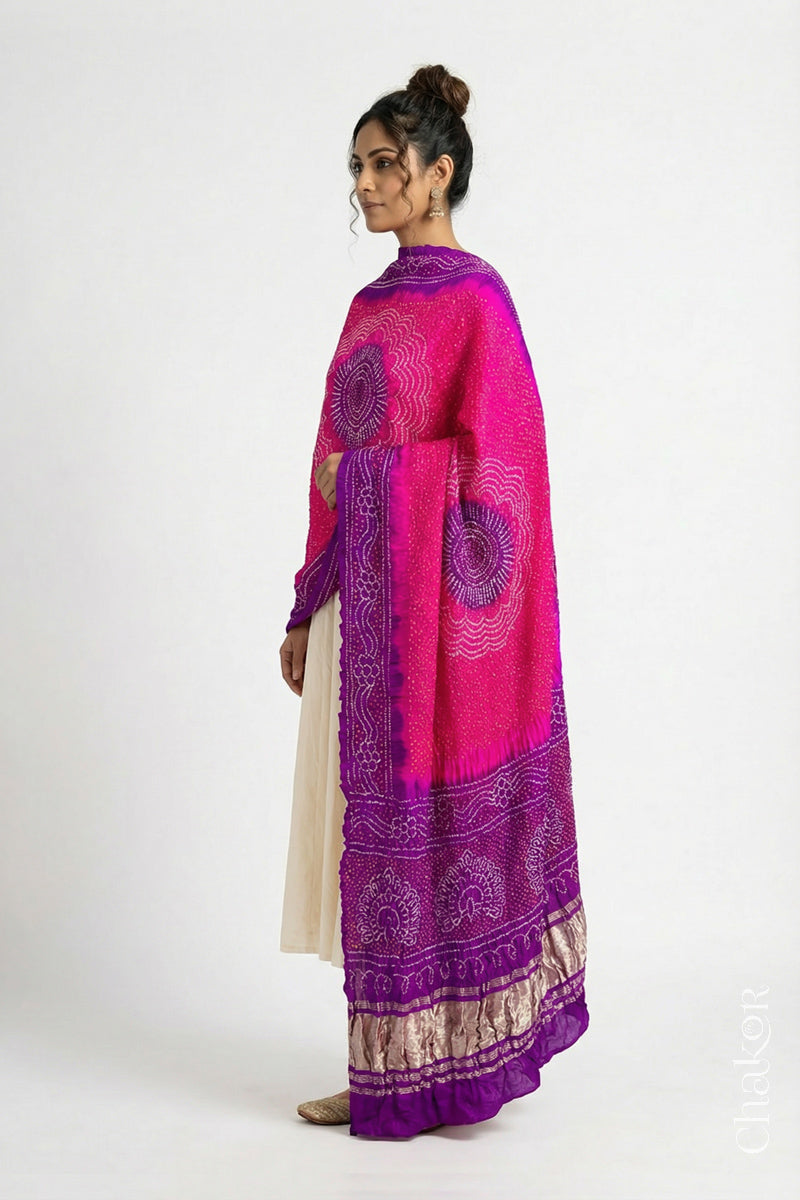 Model wearing pink and purple Bandhani gaji silk dupatta with peacock design pallu and contrast border.