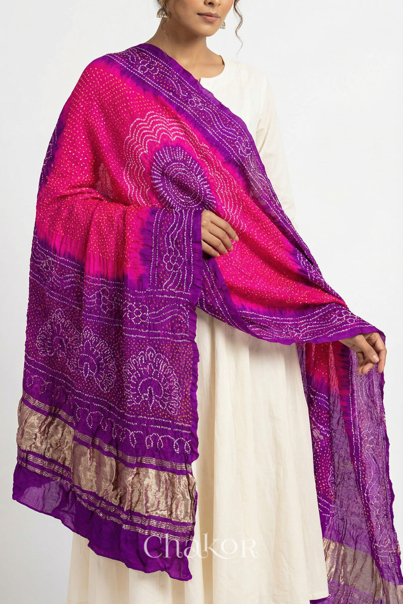 Close up of Model wearing pink and purple Bandhani gaji silk dupatta with peacock design pallu and contrast border.