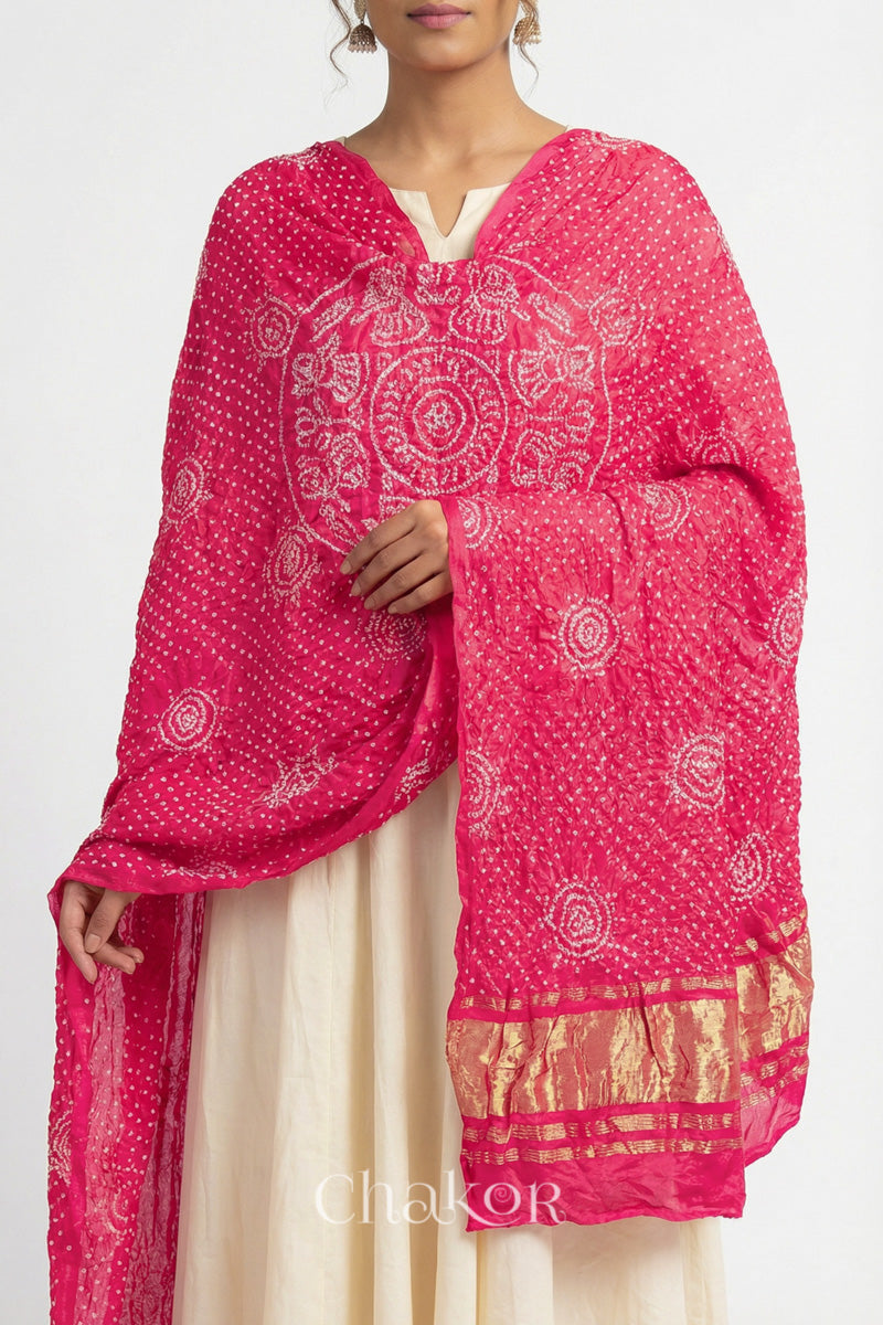 Close up of model wearing coral Bandhani gaji silk dupatta with Raas Mandal pattern and lagdi patto pallu.