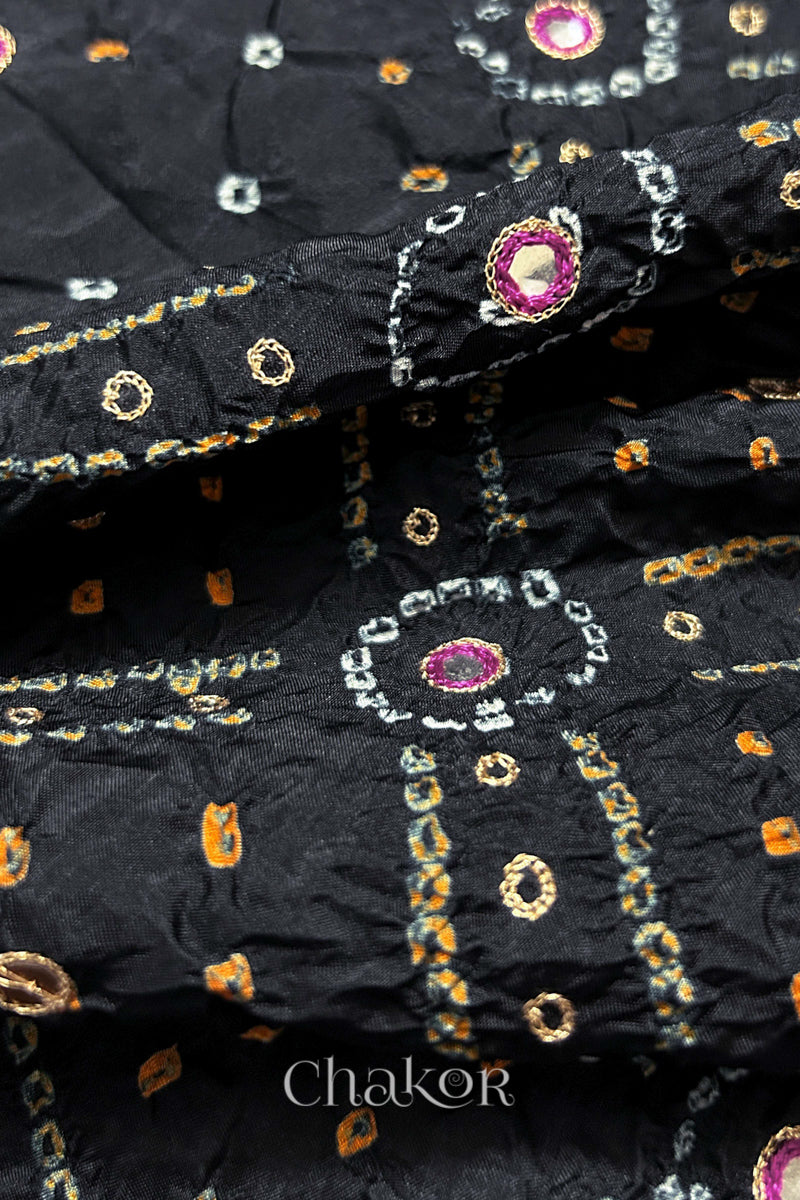 Close-up of Black mulberry silk Bandhani (Rai Bandhej) fabric with white and yellow tie-dye motifs, zari embroidered pink mirror work and sequin detailing – CHAKOR.
