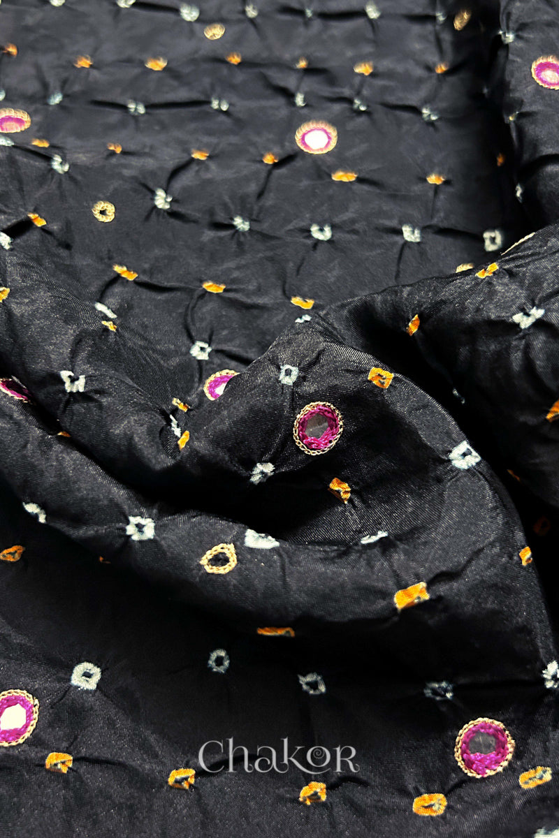 Close-up of Black mulberry silk Bandhani (Rai Bandhej) fabric with white and yellow tie-dye motifs, zari embroidered pink mirror work and sequin detailing – CHAKOR.
