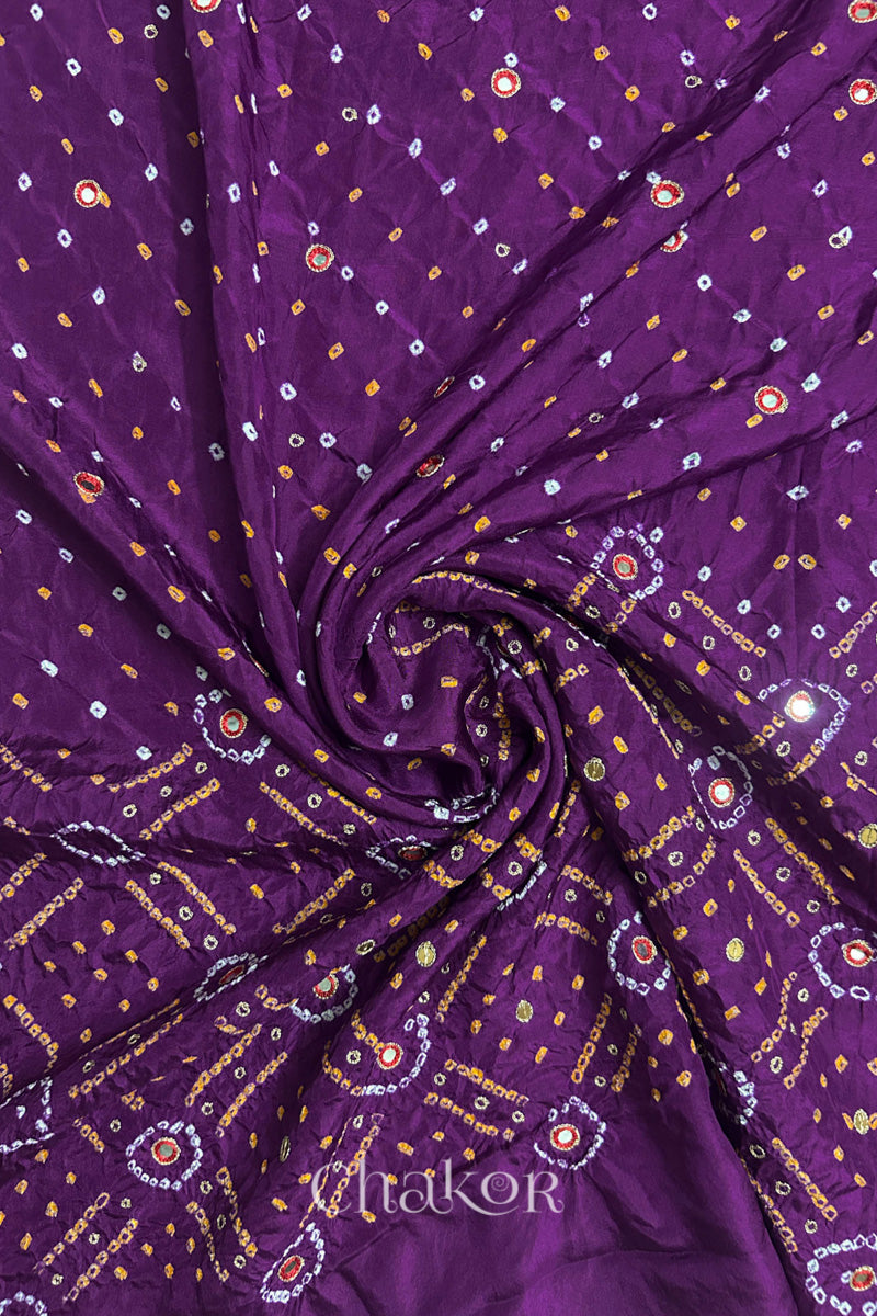 Purple mulberry silk Bandhani (Rai Bandhej) fabric with white and yellow tie-dyed motifs, red mirror and sequin embellishment, arranged in a swirling design  – CHAKOR.
