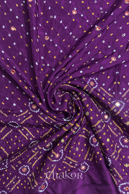 Purple mulberry silk Bandhani (Rai Bandhej) fabric with white and yellow tie-dyed motifs, red mirror and sequin embellishment, arranged in a swirling design  – CHAKOR.
