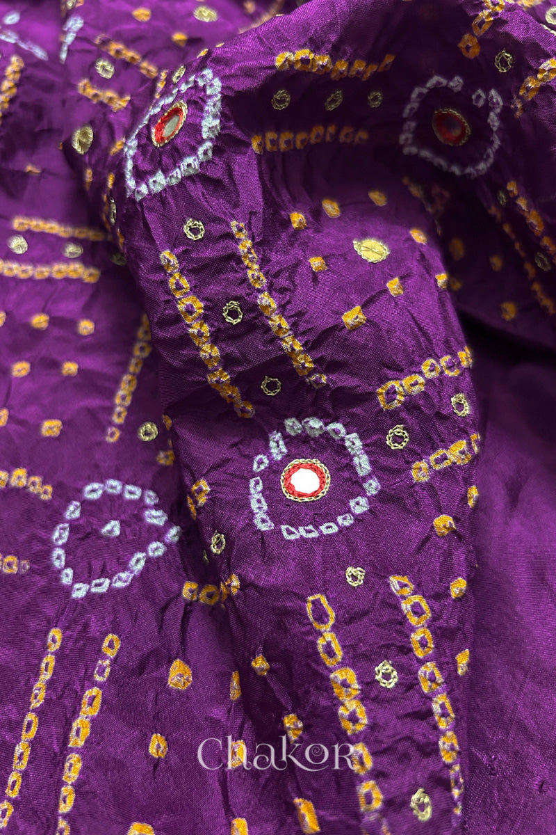 Close-up of Purple mulberry silk Bandhani (Rai Bandhej) fabric with white and yellow tie-dye motifs, red embroidered mirror work and sequin detailing – CHAKOR.
