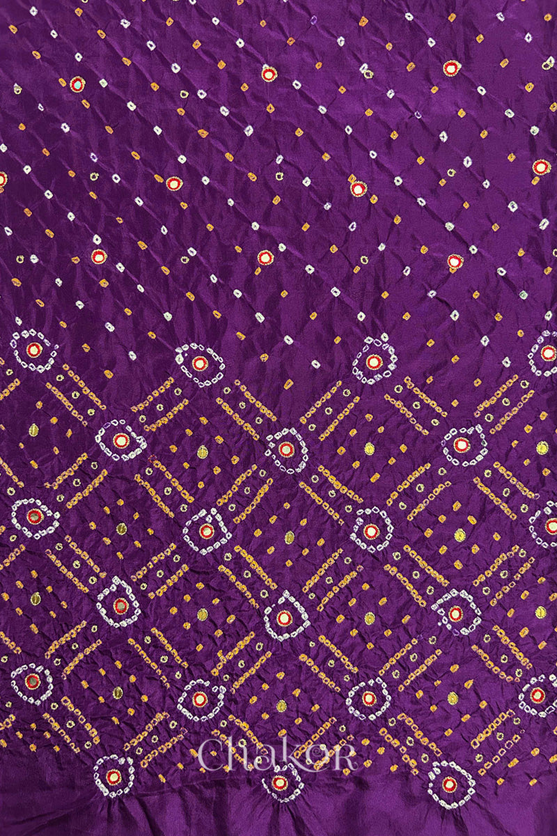 Purple mulberry silk Bandhani (Rai Bandhej) fabric showing full layout with white and mustard tie-dye butis, geometric bandhej pattern, and red mirror & sequins embroidery – CHAKOR.
