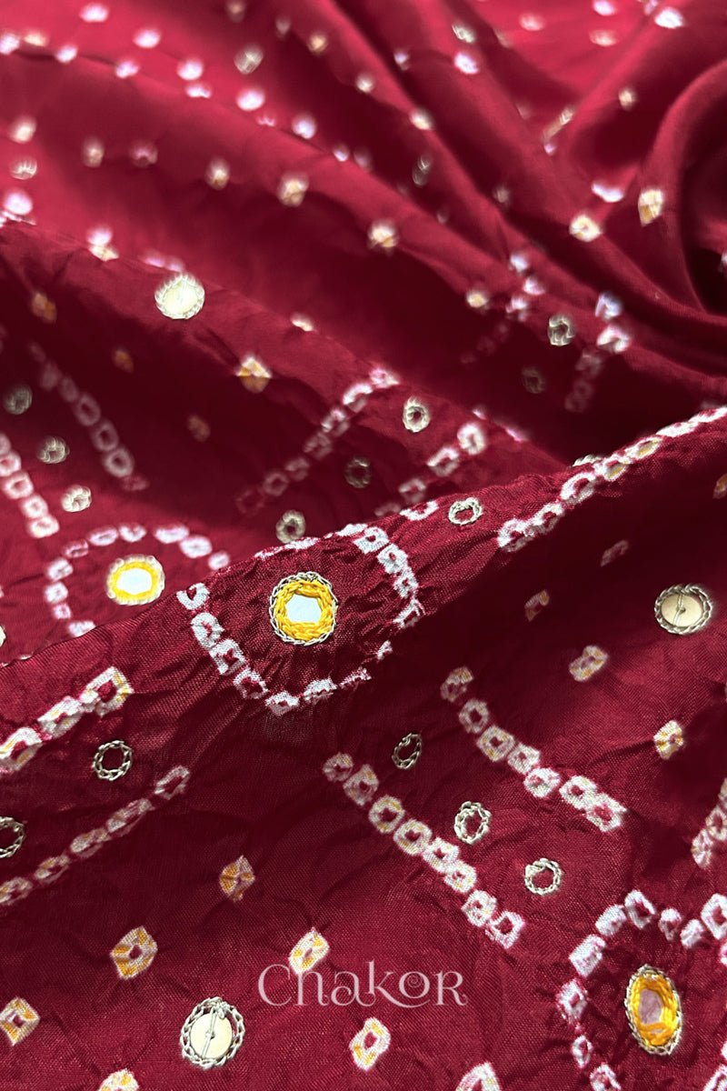 Close-up of Deep Red mulberry silk Bandhani (Rai Bandhej) fabric with white and yellow tie-dye motifs, yellow with zari embroidered mirror work and sequin detailing – CHAKOR.
