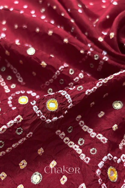 Close-up of Deep Red mulberry silk Bandhani (Rai Bandhej) fabric with white and yellow tie-dye motifs, yellow with zari embroidered mirror work and sequin detailing – CHAKOR.
