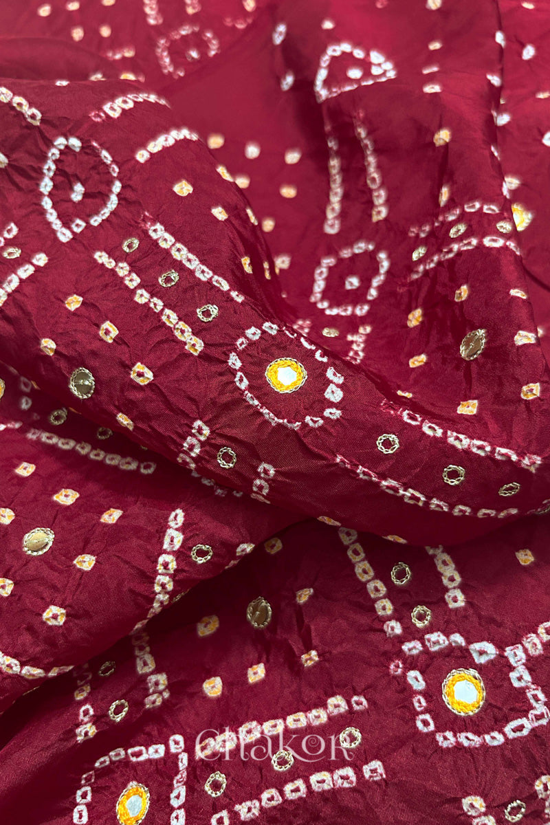 Close-up of Deep Red mulberry silk Bandhani (Rai Bandhej) fabric with white and yellow tie-dye motifs, yellow with zari embroidered mirror work and sequin detailing – CHAKOR.
