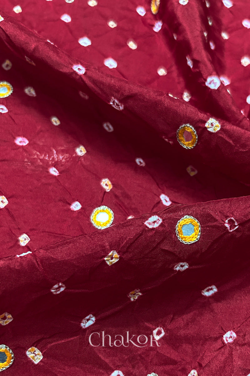 Close-up of Deep Red mulberry silk Bandhani (Rai Bandhej) fabric with white and yellow tie-dyed butis and a yellow with zari embroidered mirror motif – CHAKOR.
